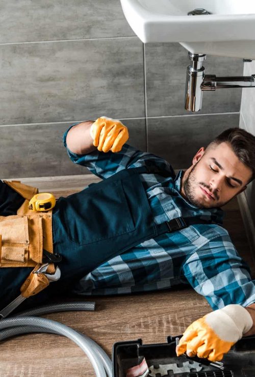 bearded-handyman-lying-on-floor-near-toolbox-in-bathroom.jpg